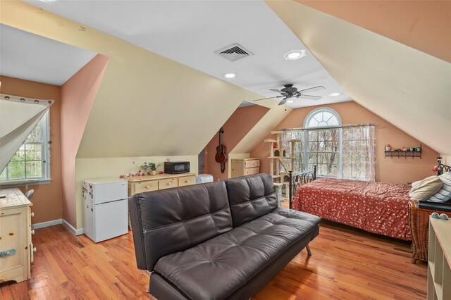 bedroom with light wood-type flooring, baseboards, lofted ceiling, visible vents, and freestanding refrigerator