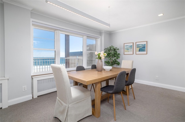carpeted dining area featuring crown molding, baseboards, healthy amount of natural light, and a water view