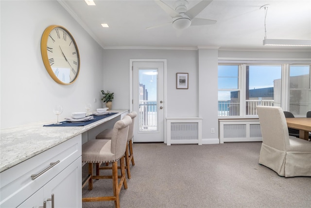 home office featuring ornamental molding, light carpet, healthy amount of natural light, built in study area, and a ceiling fan