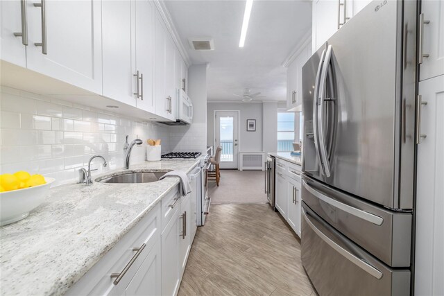 kitchen with stainless steel fridge with ice dispenser, a sink, white microwave, and white cabinetry