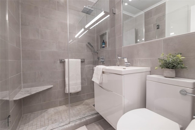 full bathroom with tile walls, toilet, tiled shower, vanity, and crown molding