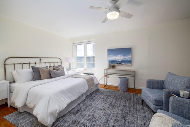 bedroom with wood finished floors, crown molding, baseboards, and ceiling fan
