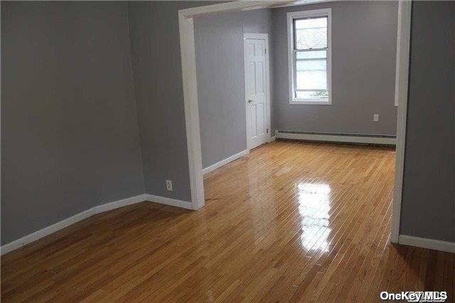 spare room with baseboard heating, baseboards, and wood finished floors