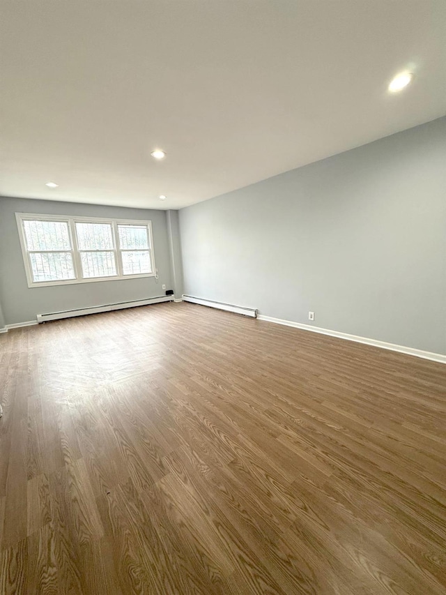 unfurnished room featuring baseboard heating, a baseboard heating unit, baseboards, recessed lighting, and wood finished floors