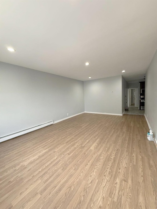 unfurnished living room with light wood-style floors, recessed lighting, baseboards, and a baseboard radiator