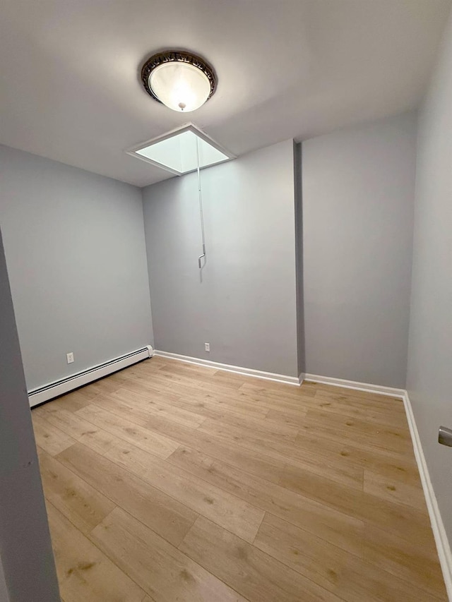 below grade area featuring light wood-type flooring, a baseboard heating unit, and baseboards