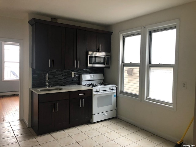 kitchen featuring gas range gas stove, stainless steel microwave, light countertops, a sink, and decorative backsplash