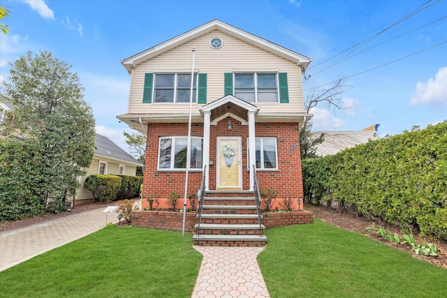 view of front of property with brick siding, a front lawn, and entry steps
