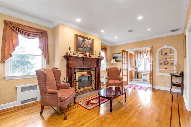 living room with radiator heating unit, plenty of natural light, wood finished floors, ornamental molding, and recessed lighting
