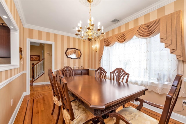 dining room with light wood-style flooring, ornamental molding, a chandelier, stairs, and wallpapered walls