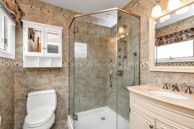full bathroom featuring tile walls, a shower stall, toilet, and vanity