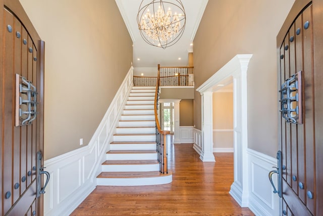 11 Victorian Ln, Brookville, NY 11545 - entryway featuring a decorative wall, crown molding, wood finished floors, a chandelier, and stairs