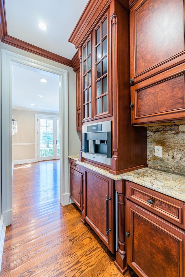 11 Victorian Ln, Brookville, NY 11545 - kitchen featuring light wood-style flooring, crown molding, backsplash, glass insert cabinets, and light stone countertops
