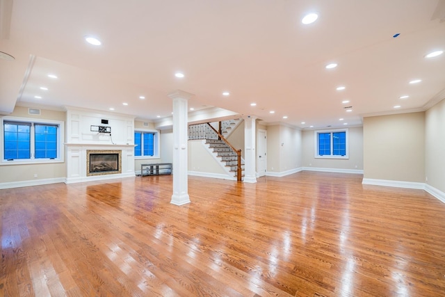 11 Victorian Ln, Brookville, NY 11545 - unfurnished living room featuring ornamental molding, decorative columns, light wood-style flooring, a glass covered fireplace, and stairway