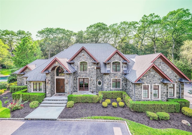 11 Victorian Ln, Brookville, NY 11545 - french country home with stone siding, a high end roof, and view of wooded area