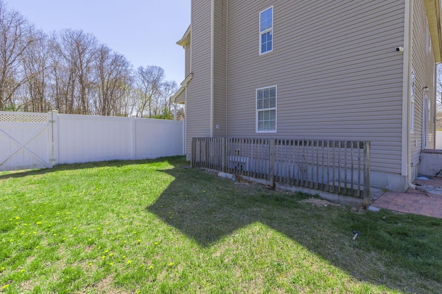 view of side of home featuring a gate, a lawn, and a fenced backyard