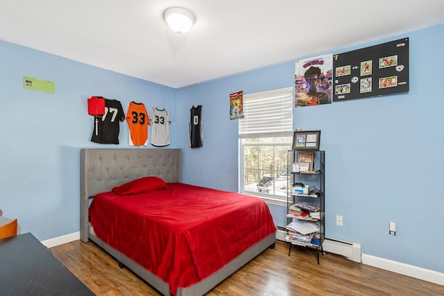 bedroom with a baseboard radiator, baseboards, and wood finished floors