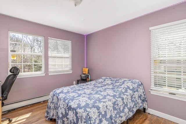 bedroom with baseboards, wood finished floors, and baseboard heating