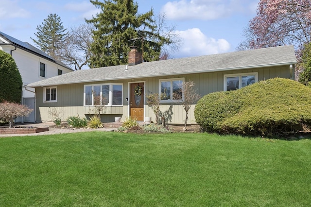 single story home featuring a shingled roof, a front yard, and a chimney