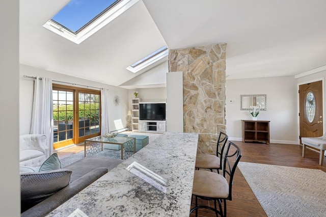 living room with baseboards, lofted ceiling with skylight, and wood finished floors