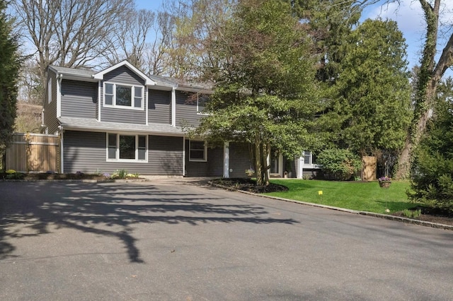 view of front of home featuring fence, a front lawn, and driveway
