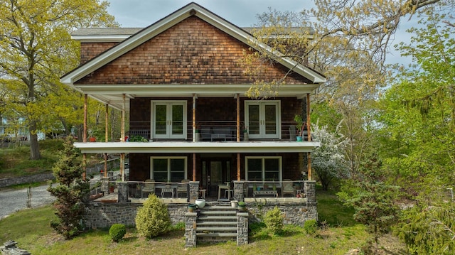 view of front of house with covered porch, french doors, a balcony, and roof with shingles