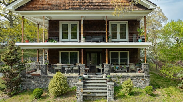 view of front facade with covered porch, french doors, a balcony, and stairs