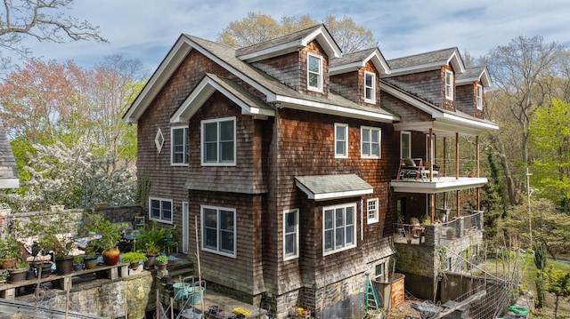 view of property exterior with roof with shingles and a balcony