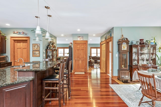 kitchen featuring a kitchen bar, hanging light fixtures, wood finished floors, a sink, and recessed lighting