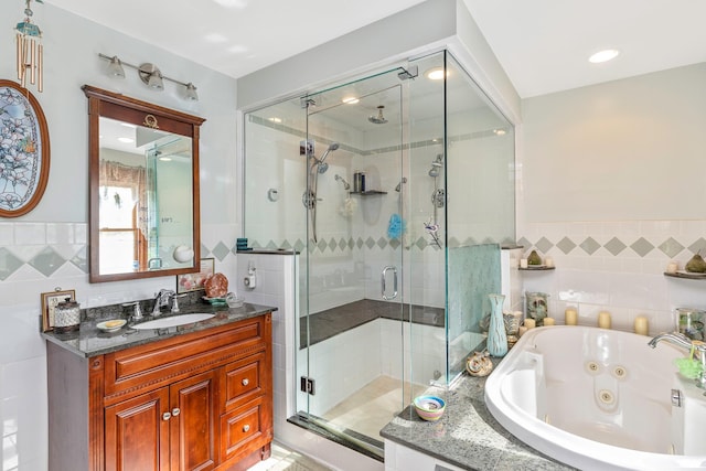 bathroom with vanity, tile walls, a jetted tub, and a stall shower