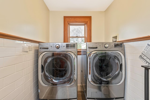 laundry room featuring laundry area, washing machine and dryer, and tile walls