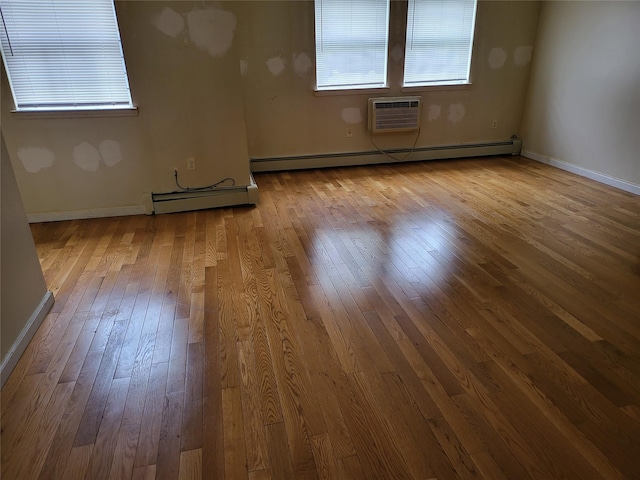 unfurnished room with wood-type flooring, baseboards, a baseboard heating unit, and a wall unit AC