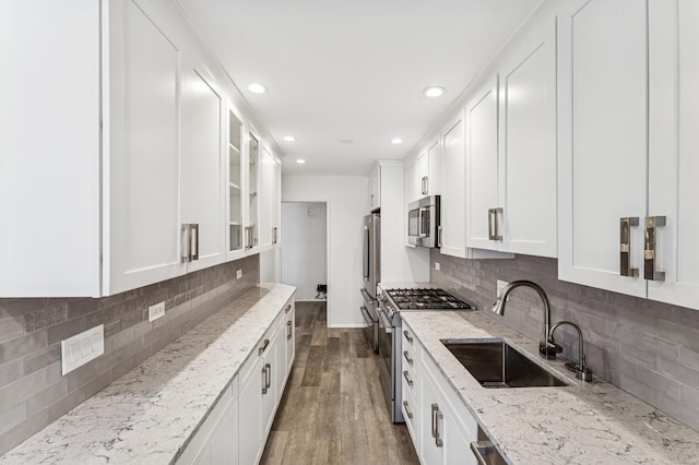 kitchen featuring dark wood finished floors, glass insert cabinets, white cabinetry, appliances with stainless steel finishes, and a sink