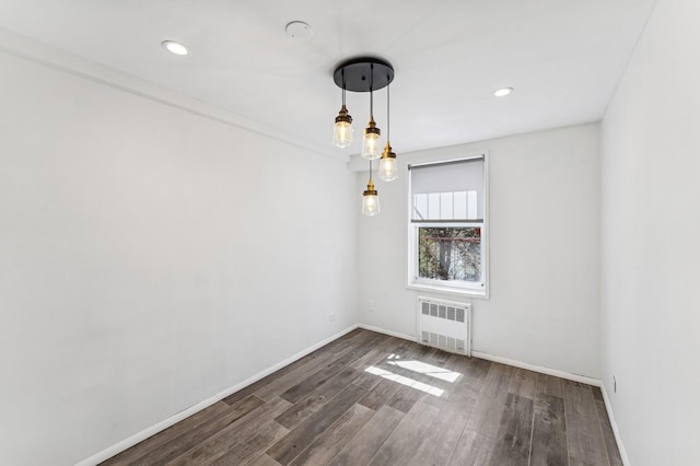 spare room with radiator heating unit, baseboards, dark wood finished floors, and recessed lighting