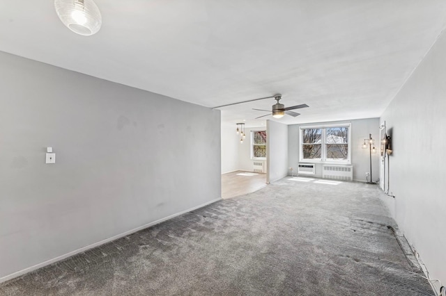 unfurnished living room featuring radiator heating unit, carpet flooring, baseboards, and a ceiling fan