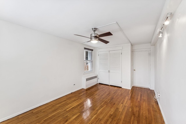 unfurnished bedroom featuring a closet, radiator heating unit, wood-type flooring, and baseboards