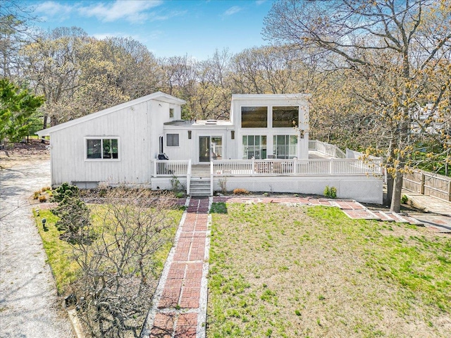 view of front of property featuring a wooden deck, a front yard, and fence