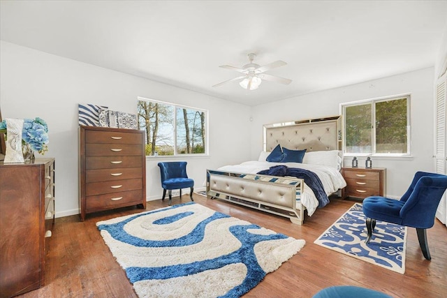 bedroom with baseboards, ceiling fan, multiple windows, and wood finished floors