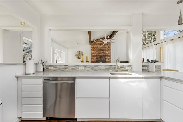 kitchen with stainless steel dishwasher, vaulted ceiling with beams, light countertops, white cabinets, and a sink