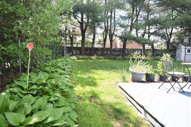 view of yard featuring a wooden deck, a storage unit, and an outdoor structure