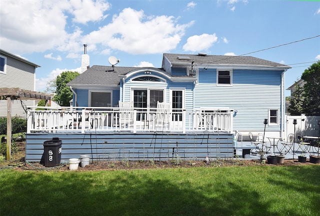 back of property with a deck, a yard, and a chimney