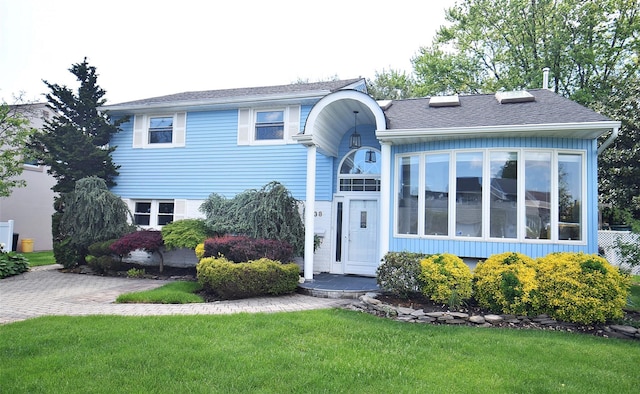 view of front facade featuring a front lawn and roof with shingles