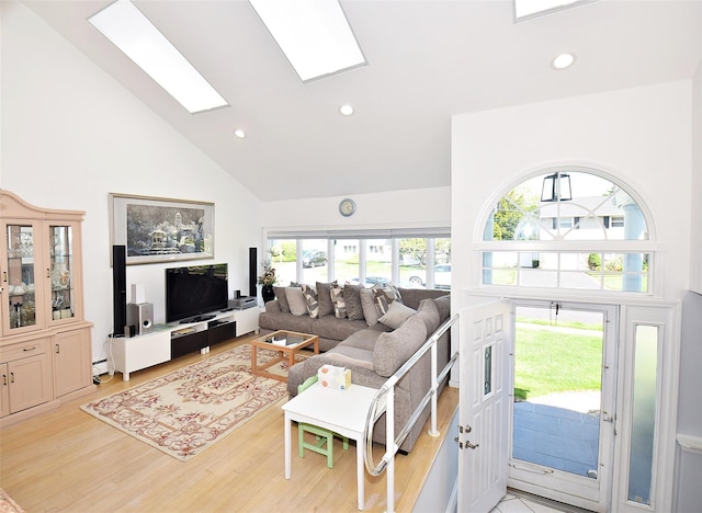 living area with high vaulted ceiling, recessed lighting, a skylight, light wood finished floors, and a baseboard heating unit