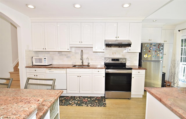 kitchen featuring appliances with stainless steel finishes, a sink, under cabinet range hood, light wood-style flooring, and white cabinets