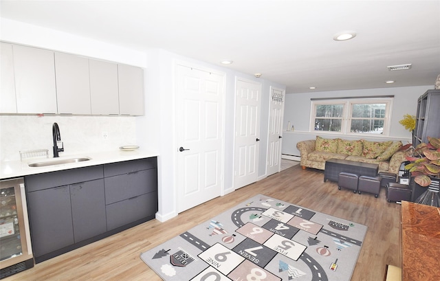 living area featuring beverage cooler, a baseboard radiator, light wood-type flooring, and recessed lighting
