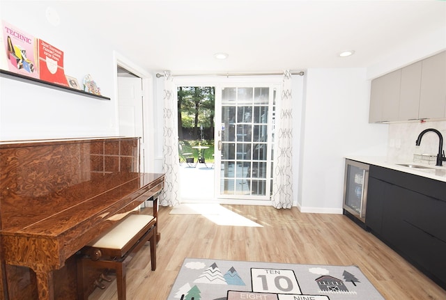 interior space featuring light wood finished floors, beverage cooler, baseboards, and recessed lighting
