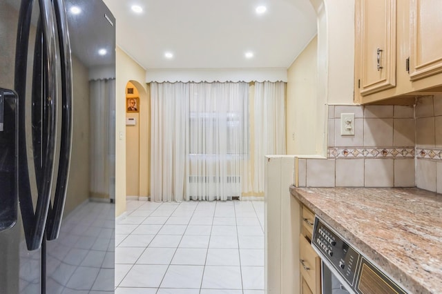 kitchen featuring arched walkways, light tile patterned floors, light countertops, and freestanding refrigerator