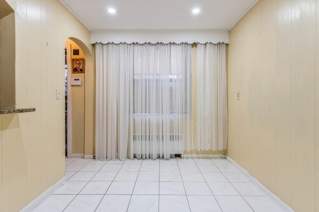 unfurnished room featuring arched walkways and baseboards