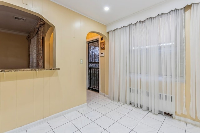 spare room with arched walkways, light tile patterned floors, crown molding, and visible vents