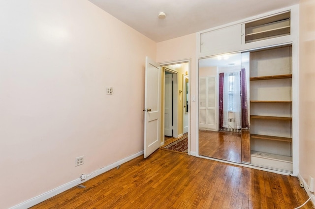 unfurnished bedroom featuring a closet, wood-type flooring, and baseboards